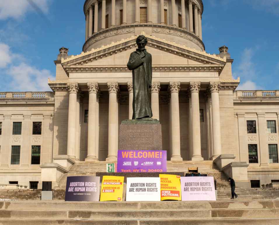 A statue of Abraham Lincoln is surrounded by protest signs outside the West Virginia Capitol