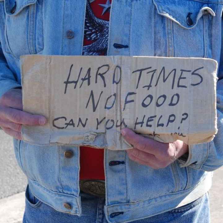 A person holds a sign that says Hard Times, No Food, Can you help?