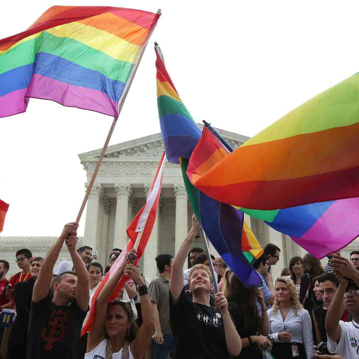 People wave rainbow flags in front of the U.S. Supreme Court building